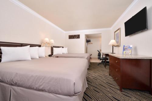 a hotel room with two beds and a desk at Hotel Heritage in El Monte