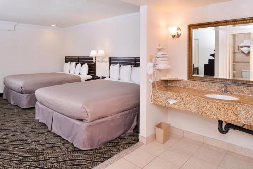 Habitación de hotel con 2 camas y espejo en Hotel Heritage, en El Monte