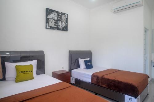 two beds sitting next to each other in a room at Urbanview keTemon Hotel & Resto YIA by RedDoorz in Yogyakarta