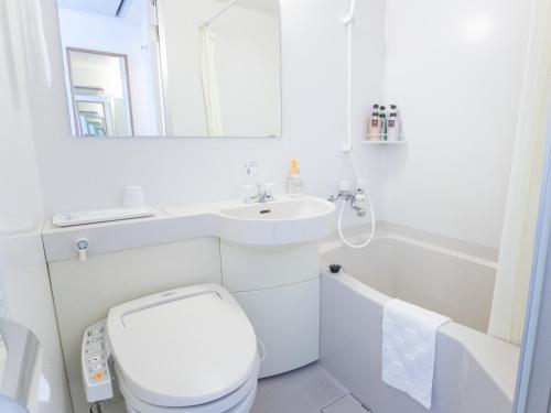 a white bathroom with a toilet and a sink at Hotel Wing Port Nagasaki in Nagasaki