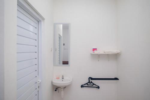 a white bathroom with a sink and a mirror at Urbanview keTemon Hotel & Resto YIA by RedDoorz in Yogyakarta