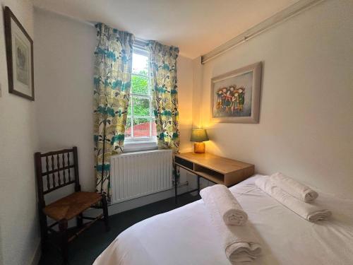 a bedroom with a bed and a chair and a window at Mews Apartments in Lincoln