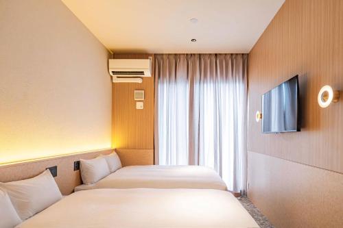 a hotel room with two beds and a television at Apartment Hotel 11 Shinsaibashi 9 in Osaka