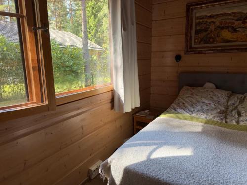 a bedroom with a bed and a window in a log cabin at Villa Lena in Kouvola