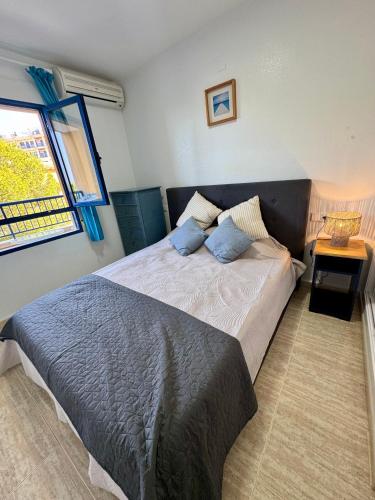 a bedroom with a bed with blue pillows and a window at Aquamarine home in Campoamor