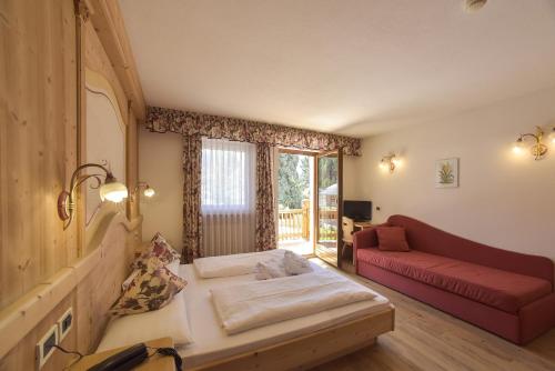 a living room with a couch and a red couch at Hotel Vajolet in San Cassiano