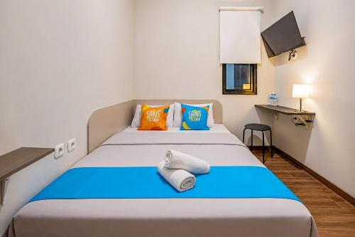 a bedroom with a bed with blue and orange pillows at Sans Stay Bintaro in Pondoklang