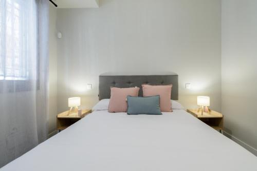 a bedroom with a large bed with pink and blue pillows at Torrejón Suites in Torrejón de Ardoz