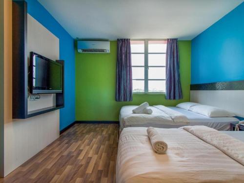 a room with two beds and a flat screen tv at e Hotel in Malacca