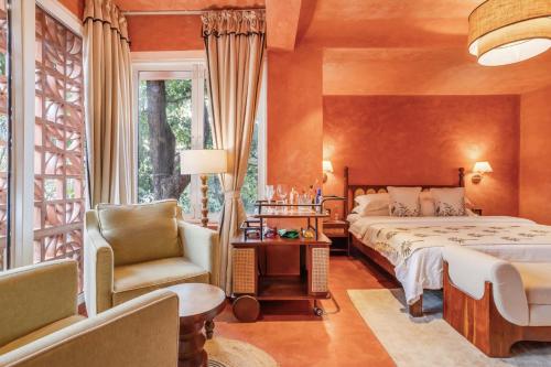 a bedroom with a bed and a chair and a window at Unseen Boutique Hotel, Assagao in Assagao