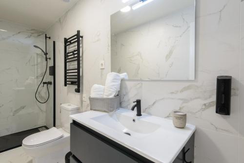 a white bathroom with a sink and a toilet at Torrejón Suites in Torrejón de Ardoz