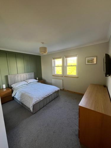a bedroom with a large bed and two windows at Crofters Cottage Barra 