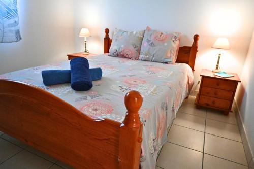 a bedroom with a wooden bed with blue pillows at Ti' Palmiers in Pointe-Noire