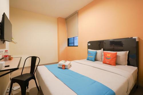 a room with a bed with a desk and a chair at Sans Hotel Beskalan Malioboro in Yogyakarta
