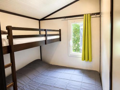 a bedroom with two bunk beds and a window at Chalet privilège Parc de la Chesnaie in Autruy-sur-Juine