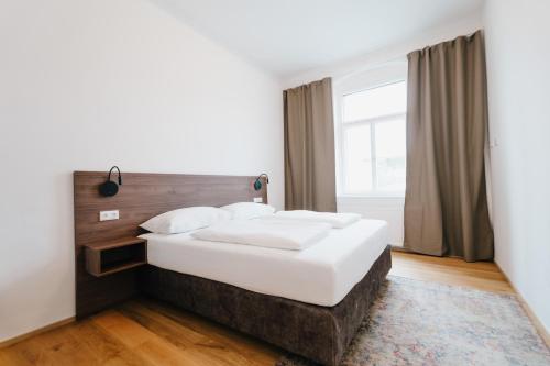 a bedroom with a large white bed and a window at Rilke Apartments in Linz