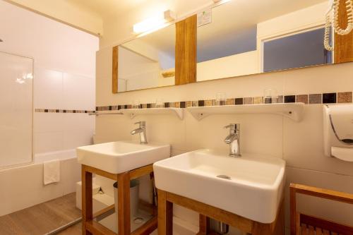 a bathroom with two sinks and a mirror at Hôtel Colisée-Verdun Centre Gare Saint-Roch in Montpellier