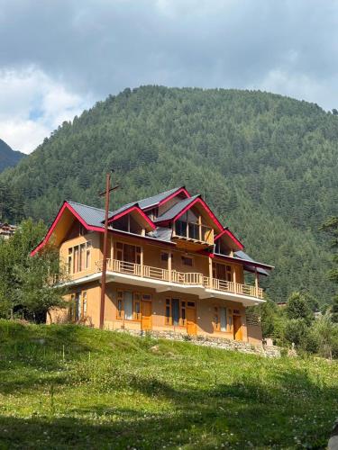 a large house on a hill with a mountain at Flamingo Aur Maina Stays - Jibhi in Jibhi