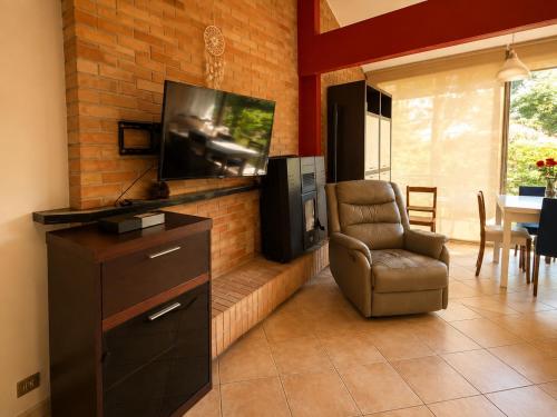 a living room with a television and a chair at Villa Pineta Grande in Lignano Sabbiadoro