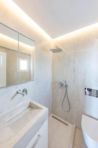 a white bathroom with a shower and a sink at Ibiscus down town location Myconos in Megali Ammos