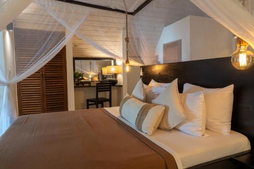 a bedroom with a bed with white pillows at Jambiani Villas in Jambiani