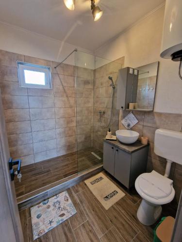 a bathroom with a shower and a toilet and a sink at Porto Lima in Limanu