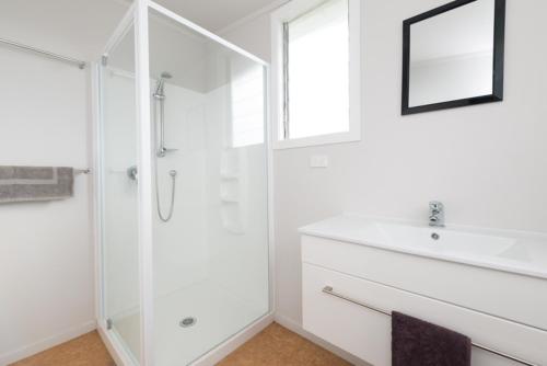 a white bathroom with a sink and a shower at Russell-Orongo Bay Holiday Park in Russell