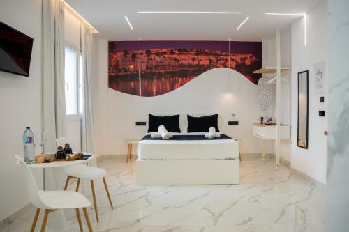 a white bedroom with a bed and a painting on the wall at Apartamentos Alsa in Conil de la Frontera