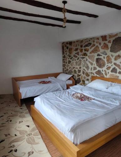 two beds in a room with a stone wall at SRC Bella Casa in Ohrid