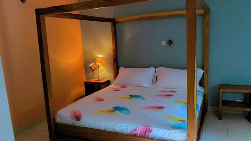 a bedroom with a canopy bed with flowers on it at Samba immo chez Mbaye in Fatick