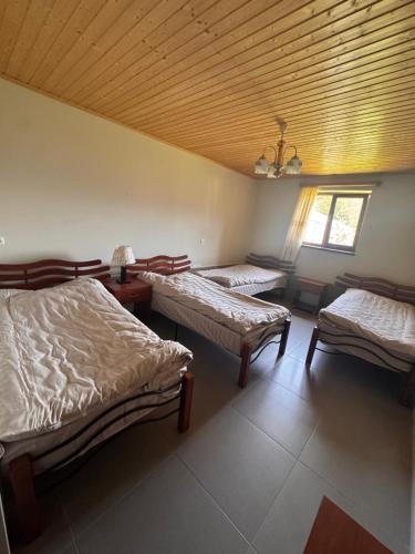 a room with three beds and a wooden ceiling at Guesthouse Lasili in Mestia in Mestia