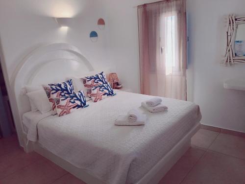 a bedroom with a white bed with towels on it at Palio Karnagio Παλιό Καρνάγιο in Koufonisia