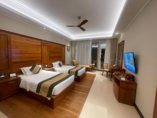 a hotel room with two beds and a flat screen tv at Grand Hotel Villa Ella in Bandarawela