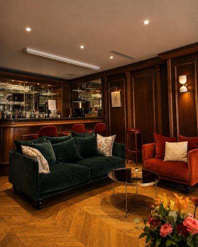 a living room with a green couch and a bar at Hôtel Derby Eiffel in Paris