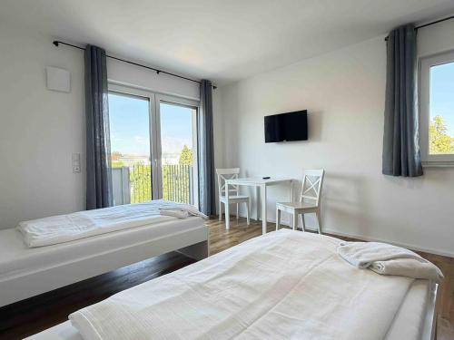 a bedroom with two beds and a table with a television at AM102 moderne Monteurwohnung in Amberg