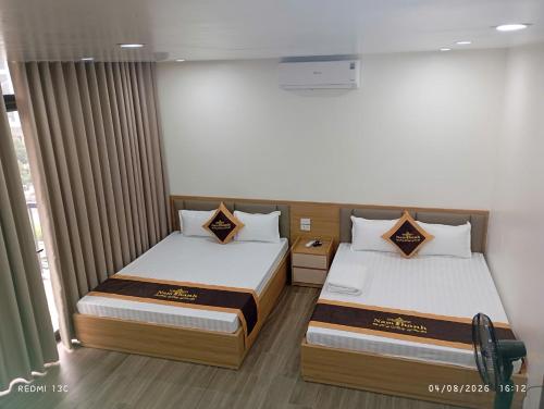 two beds in a small room with curtains at Nam Thanh Hotel in Nhật Tựu