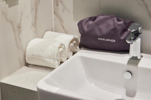 a bathroom with a white sink and a towel at Hotel HLB in Busan