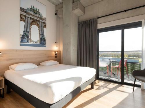 a bedroom with a large bed and a large window at ibis Styles Namur in Namur