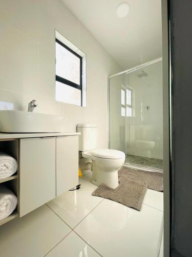 a white bathroom with a toilet and a sink at MAISON MOSH ll GUEST HOUSE in Maseru