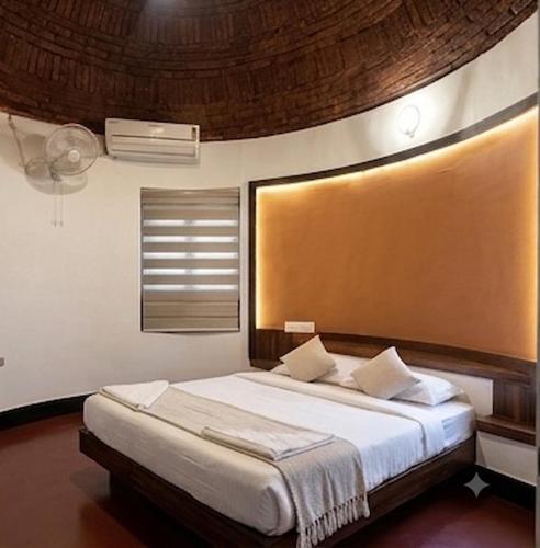a bedroom with a large bed with a wooden headboard at Vayal Heritage Villa in Angamaly