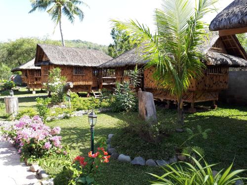 a resort with a building with a palm tree and flowers at Calayo Beach Resort in Nasugbu