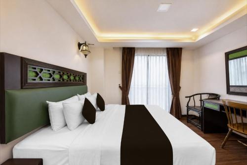 a bedroom with a large bed with a desk at Swiss Heritage Boutique Hotel Jonker Street Melaka in Malacca