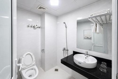 a white bathroom with a toilet and a sink at Mama Cao Bang Hotel in Cao Bằng