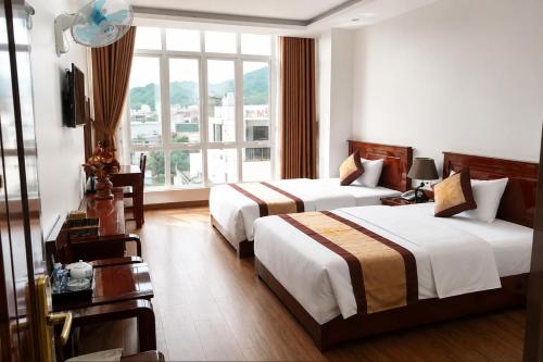a hotel room with two beds and a window at Mama Cao Bang Hotel in Cao Bằng