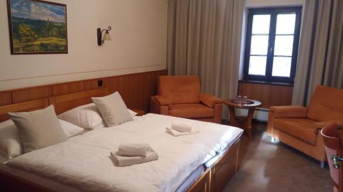 a bedroom with a bed and two chairs in it at Hotel Zámeček Pod Hradem Starý Jičín 111 in Starý Jičín