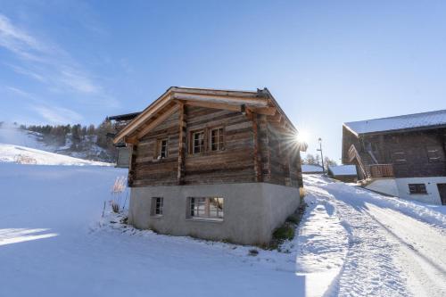 a wooden house in the snow with the sun shining at Rumpelstilzchen in Bettmeralp