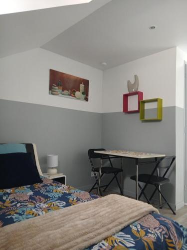 a bedroom with a bed and a table with chairs at Le Trait d'union - Studio César, 2éme Étage in Romilly-sur-Seine