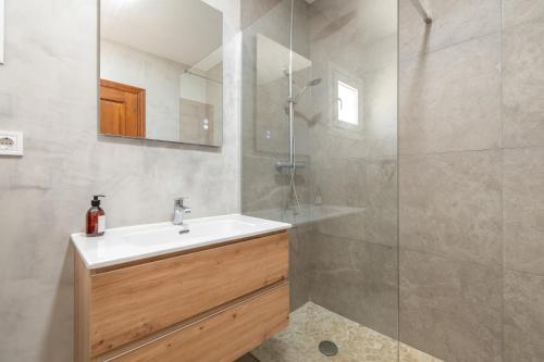 a bathroom with a sink and a glass shower at Villas2meet Los Geranios in Cala Romàntica