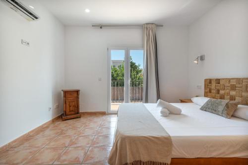 a bedroom with a large bed and a balcony at Villas2meet Los Geranios in Cala Romàntica