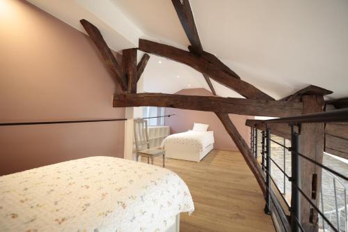 a attic bedroom with a bed and a chair at Maison Camélia in Paliseul